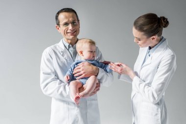 pediatricians taking care of little baby on grey clipart
