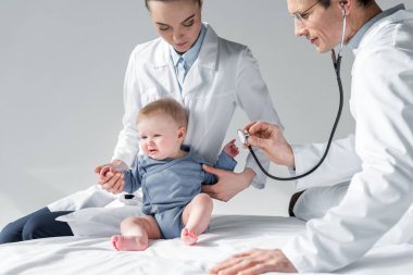 Çocuk hekimleri hüzünlü bebek yatakta nefes kontrol etmek çalışıyor