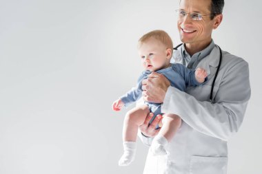 gri izole küçük bebek tutan yakışıklı yetişkin çocuk doktoru