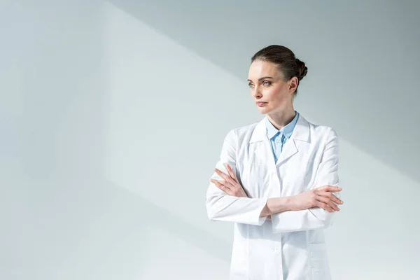Atraente Médico Feminino Com Braços Cruzados Olhando Para Longe Cinza — Fotografia de Stock