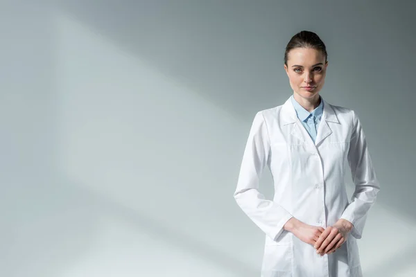 Médico Fêmea Grave Casaco Branco Olhando Para Câmera Cinza — Fotografia de Stock