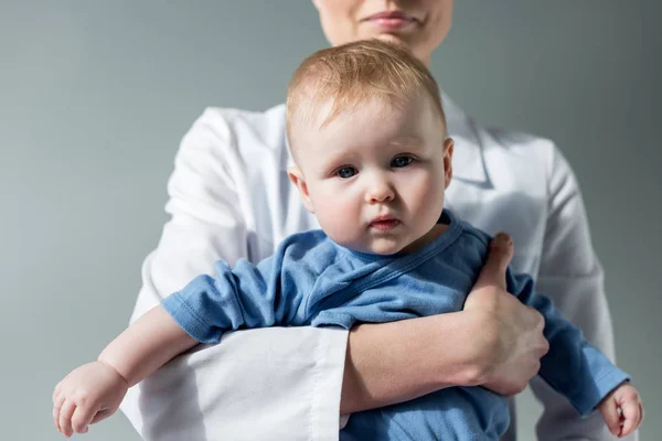 女性儿科医生拍摄的照片抱着美丽的小宝宝灰色 — 图库照片