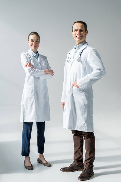 happy adult doctors looking at camera on white