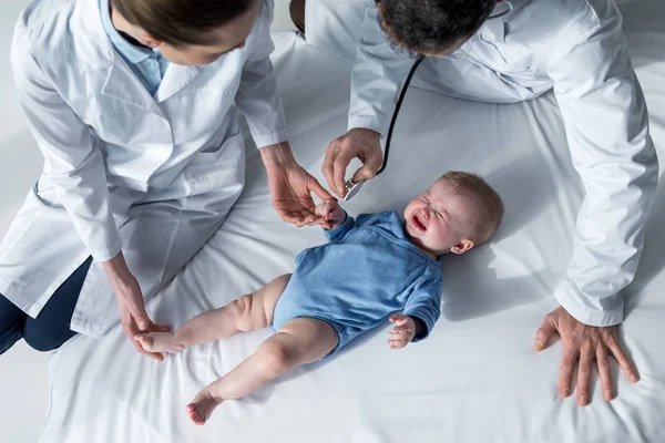 泣いている赤ちゃんの息をチェックしようと小児科医のハイアングル — ストック写真