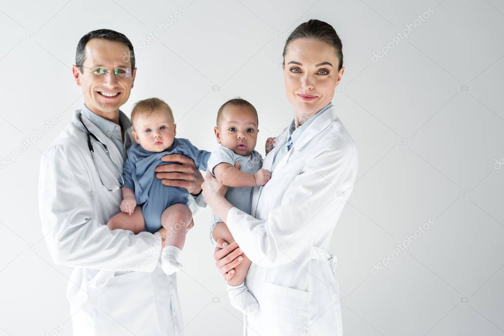 pediatricians holding little babies and looking at camera isolated on white