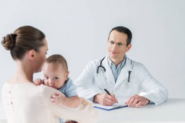 Anne ve çocuk doktoru ofisteki sevimli küçük çocuk