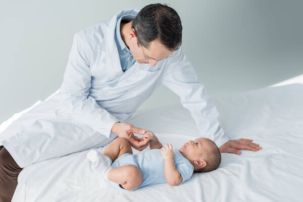 adult pediatrician sitting on bed with little baby