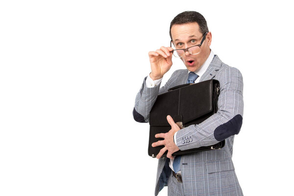 shocked adult businessman with briefcase looking at camera over glasses isolated on white