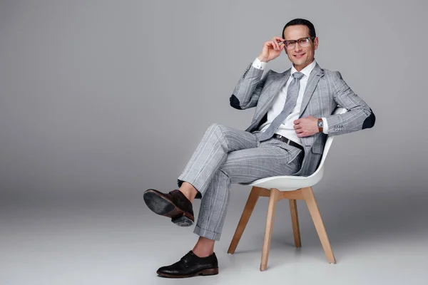 スタイリッシュなスーツ グレーの椅子に座っての笑顔の大人ビジネスマン — ストック写真