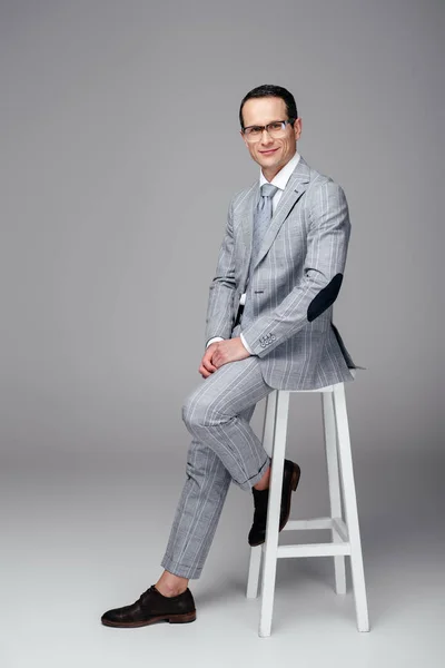 Schöner Erwachsener Geschäftsmann Eleganten Anzug Sitzt Auf Stuhl Auf Grau — Stockfoto