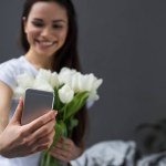 Brünettes Mädchen macht Selfie von sich mit weißen Tulpen