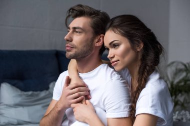 Young attractive couple hugging in bedroom and looking away clipart
