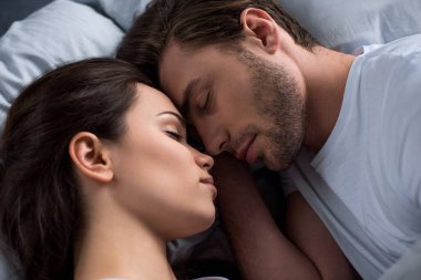 Happy young couple sleeping in bed clipart