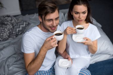 Gülümseyen erkek ve kadın yatakta kahve içme