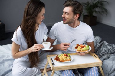Kahve içme ve yemek güzel genç çift yatakta kahvaltı