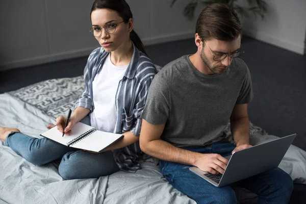 Nadenkende Man Vrouw Schrijven Kladblok Het Werken Laptop Zittend Bed — Stockfoto