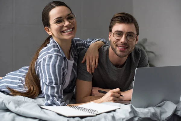 Smiling Couple Glasses Writing Notepad Working Laptop While Lying Bed — Stock Photo, Image