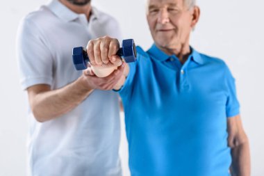 Komuta sizde gri izole dumbbell ile egzersiz yardımcı rehabilitasyon terapist kısmi görünümünü
