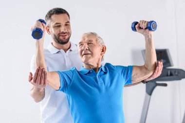 Komuta sizde gri zemin üzerinde dumbbells ile egzersiz yardımcı rehabilitasyon terapist portresi