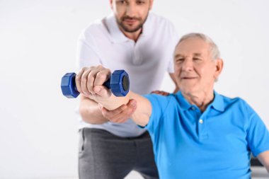 Komuta sizde gri izole dumbbell ile egzersiz yardımcı rehabilitasyon terapistin seçici odak