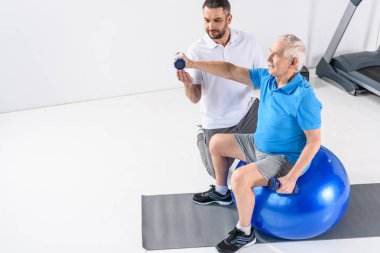 Komuta sizde fitness Ball dumbbells ile egzersiz yardımcı rehabilitasyon terapist yüksek açılı görünüş