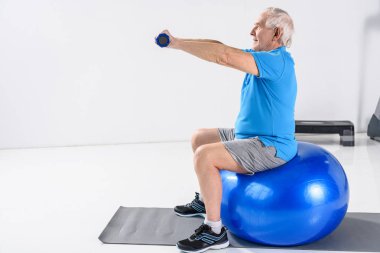 Komuta sizde fitness Ball gri zemin üzerinde egzersiz dumbbells ile yan görünüm