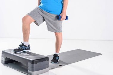 Komuta sizde gri izole Step üzerinde egzersiz dumbbells ile kısmi görünümünü