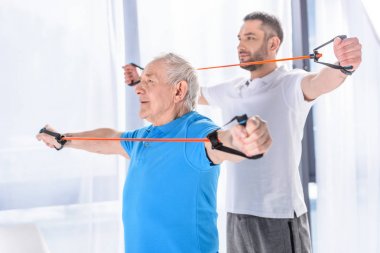 seçici odak rehabilitasyon terapist ve kıdemli insanın kauçuk şeritler, egzersiz