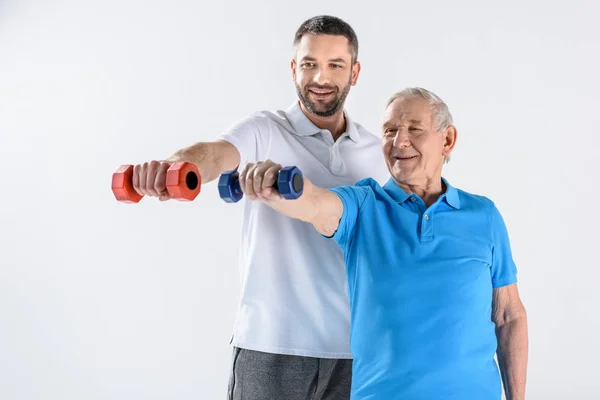 Retrato Terapeuta Rehabilitador Sonriente Hombre Mayor Haciendo Ejercicio Con Mancuernas —  Fotos de Stock