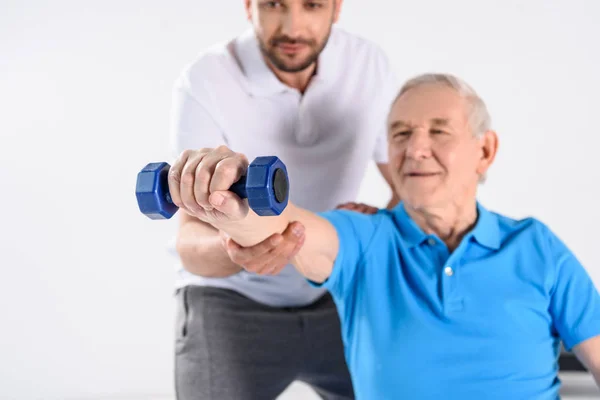 Foco Seletivo Terapeuta Reabilitação Auxiliando Homem Idoso Exercitar Com Halteres — Fotografia de Stock