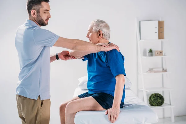 Sidovy Rehabilitering Terapeut Gör Massage Till Senior Mannen Massagebänk — Stockfoto