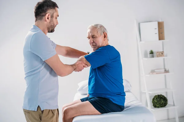 Seitenansicht Des Physiotherapeuten Der Einen Älteren Mann Auf Einem Massagetisch — Stockfoto