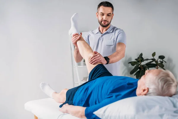 Retrato Terapeuta Reabilitação Massageando Perna Homem Sênior Mesa Massagem — Fotografia de Stock