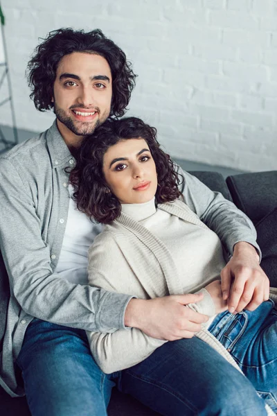 Young Couple Hugging Sofa Looking Camera Home — Free Stock Photo