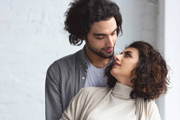 tender young couple looking at each other at home