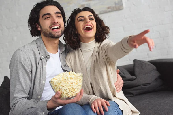 Rindo Jovem Casal Segurando Tigela Com Pipocas Assistindo Comédia Casa — Fotografia de Stock