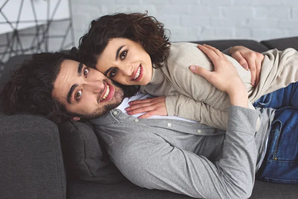 Smiling Young Couple Hugging Lying Sofa Home — Free Stock Photo