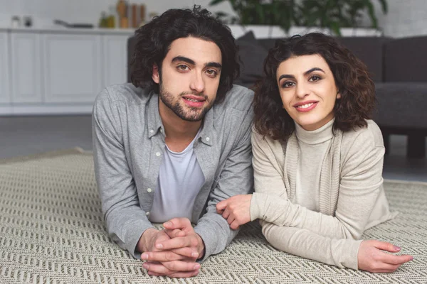 Lachende Jong Koppel Vloer Liggen Kijken Naar Camera Thuis — Stockfoto