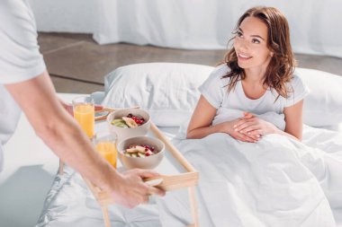 Kısmi adam görünümünü kız gülümseyerek için yatakta kahvaltı getirdim