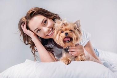 yorkshire terrier gri izole yatakta istirahat ile genç gülümseyen kadın portresi