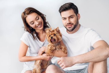 portrait of young smiling couple with yorkshire terrier isolated on grey clipart