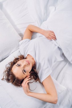 genç güzel kadın yatakta yatan ise kameraya bakarak havai görünümü