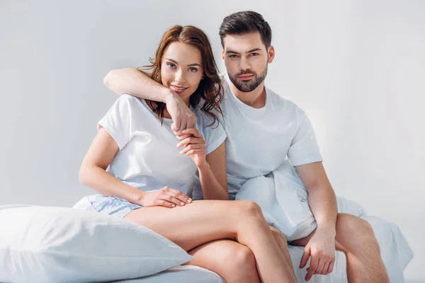 Portret Van Man Knuffelen Vriendin Zittend Bed Samen Geïsoleerd Grijs — Stockfoto