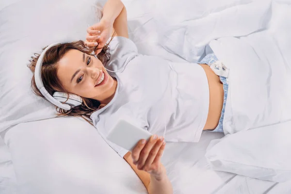 Overhead View Young Smiling Woman Headphones Using Smartphone Bed — Stock Photo, Image