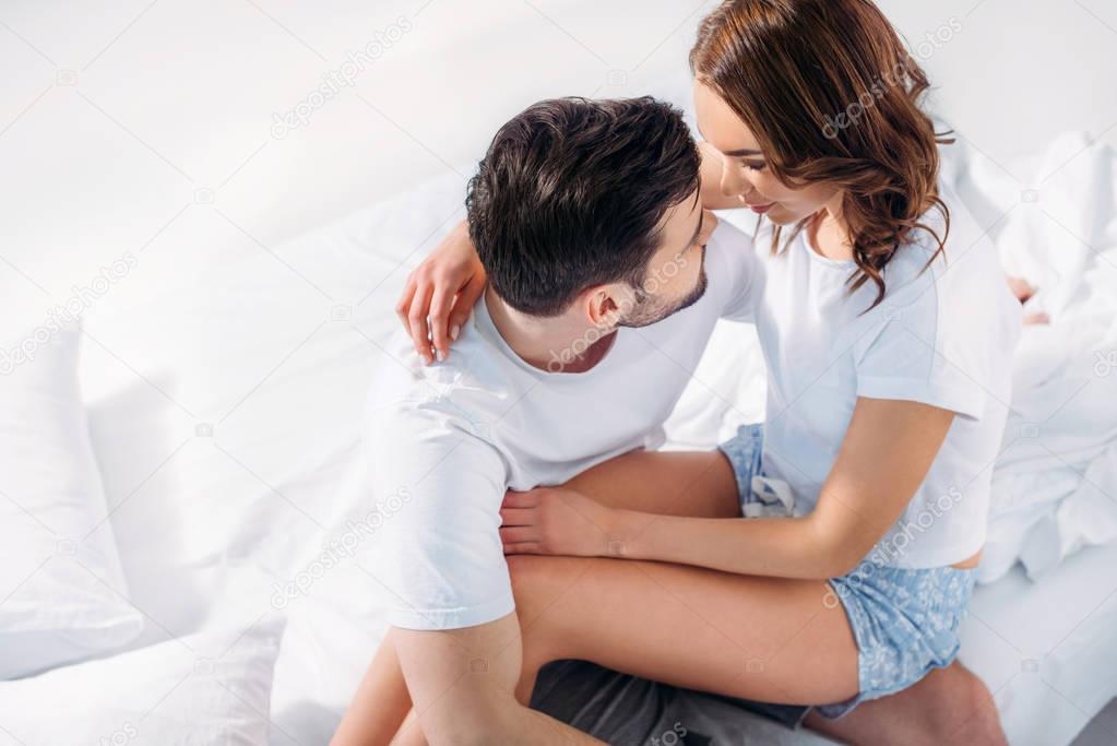 high angle view of woman sitting on boyfriends knees on bed