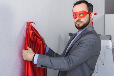super businessman wearing mask and cape in office  clipart