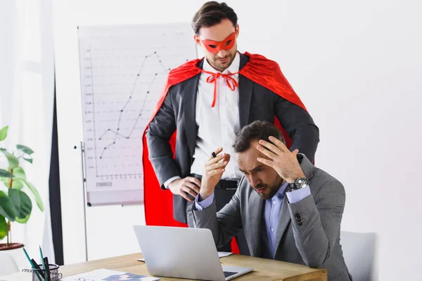超级商人在面具和海角帮助愤怒的商人在办公室工作 — 图库照片