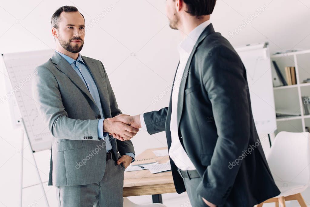 handsome businessmen shaking hands in office