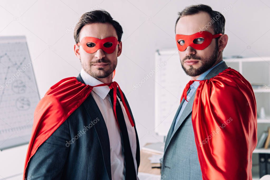 portrait of handsome super businessmen in masks and capes in office