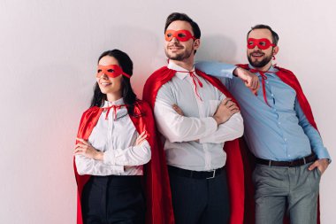 smiling super businesspeople in masks and capes looking away isolated on white